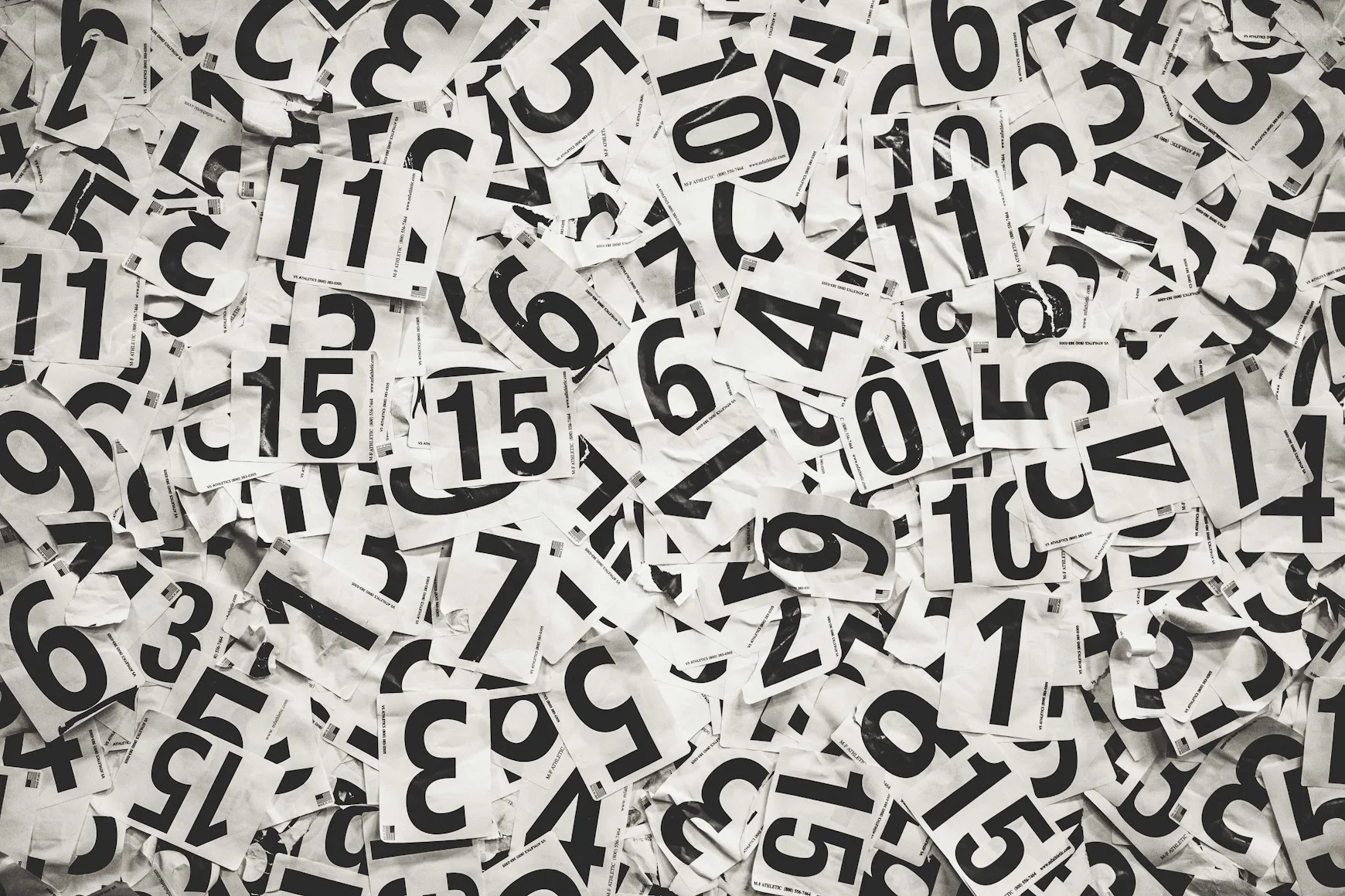 Scattered black handwritten numbers on white paper — Photo by Cooper Hofmann on Unsplash