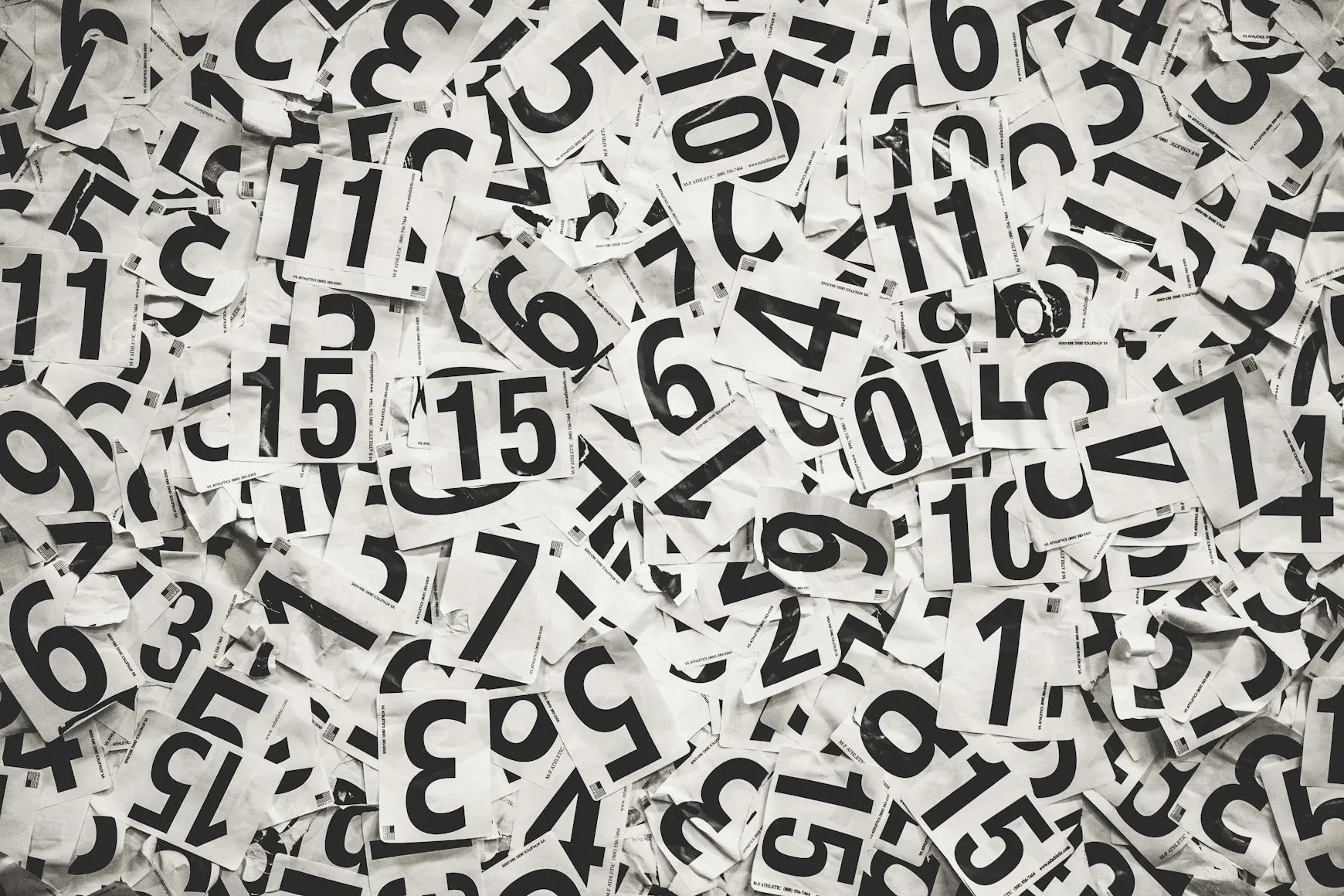 Scattered black handwritten numbers on white paper — Photo by Cooper Hofmann on Unsplash